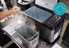 the zojirushi bread maker with someone putting water into the bread pan