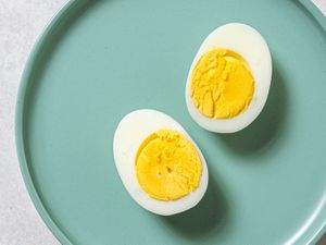 A perfect steamed boiled egg, cut in half lengthwise, on a blue plate.