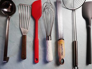 a variety of kitchen tools and utensils on a blue surface