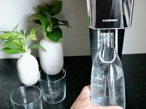 A hand loading a bottle onto the SodaStream Art