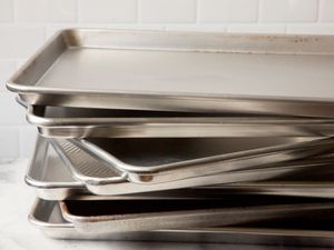 A stack of half-sheet pans in front of a gray tiled wall