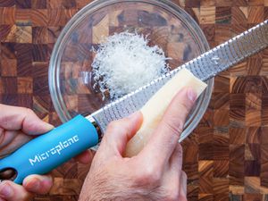 grating parmesan cheese with a blue microplane