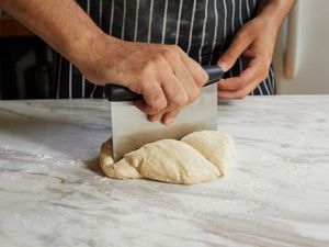 using the oxo bench scraper to cut up pizza dough