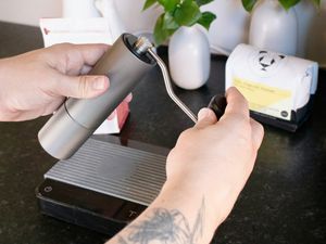 a handheld grinder is being held and cranked