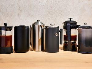 Six coffee makers on a wooden surface against grey background