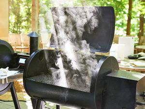 the lid of a pellet grill open and it releasing smoke 