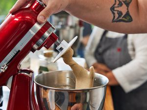 A hand holding a red stand mixer's tilt-head upright