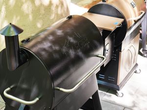 two pellet grills (one black, one bronze) side-by-side